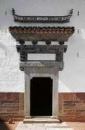 Yin Yu Tang's formal entrance penetrates a stone and brick masonry curtain wall.
