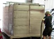 After applying a release agent and a waterproofing layer to a male mold, a worker encapsulates the liner and steel reinforcing frame in polyurethane spray foam. Completed tanks range in size from 5 by 5 by 4 feet to 8 by 8 by 20 feet.
