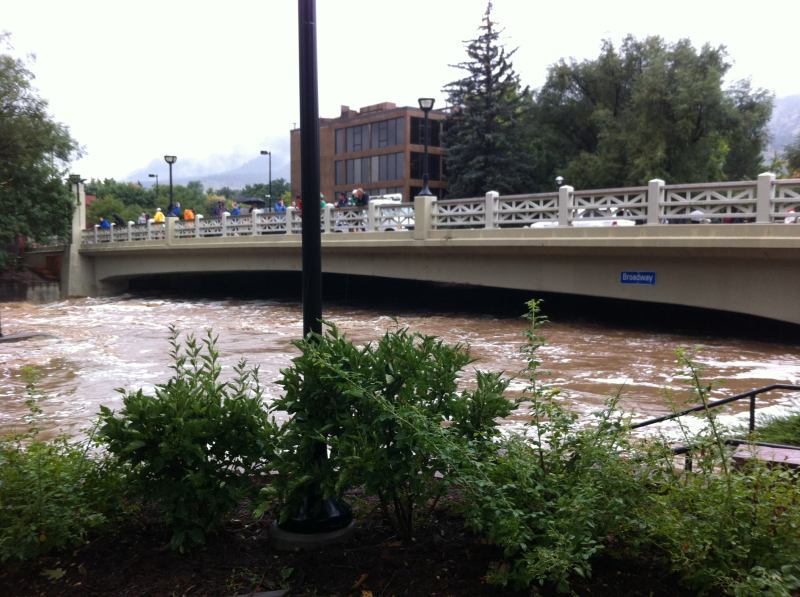 Boulder Creek rising under a bridge in downtown Boulder. Deep beneath the floodwaters are multiple lanes of bike and walking paths and a tall scenic waterfall.