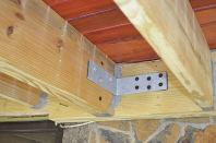 On a second-story deck, a building inspector may accept galvanized L-brackets fabricated from 1/4-inch steel and attached to the deck framing and house framing with structural screws as shown, in lieu of the threaded-rod hold-down anchors contained in the IRC.