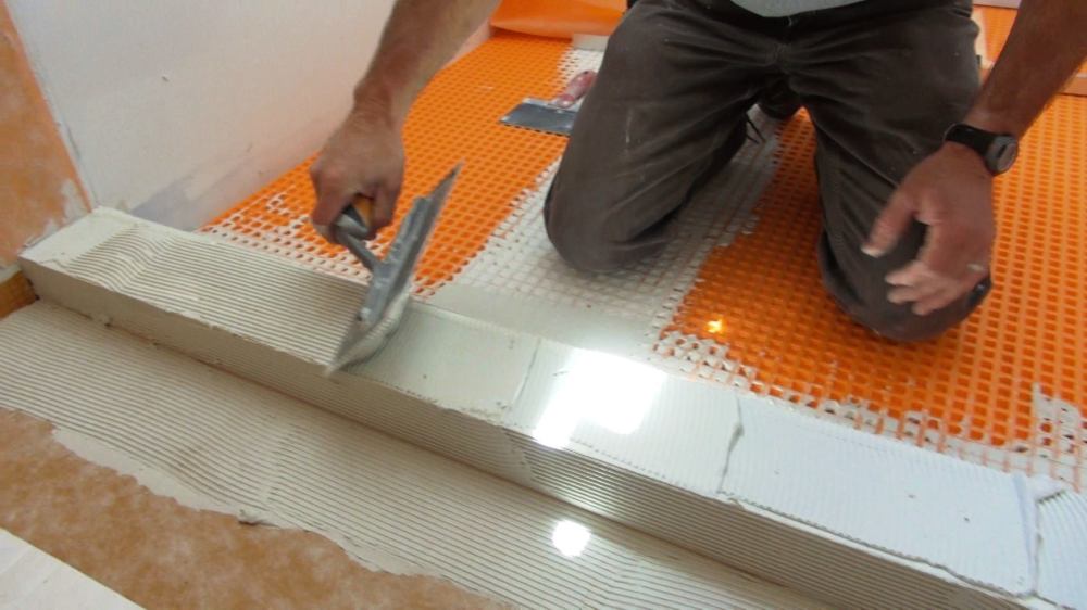 Tom Boucher trowels a measured amount of mortar onto a laminated Kerdi-Board shower curb using a Kerdi trowel with 1/8-inch teeth.