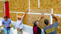 Architect Richard Pedranti, HERS rater Pete Vargo, consultant Bryan Kehm, and builder Rob Ciervo tape plastic over the OSB sheathing during a blower-door test.