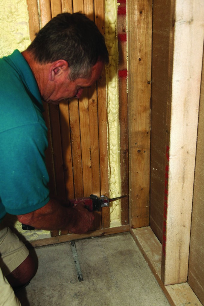 To make room for the folded shower-pan membrane in the corners, first make shallow cuts in the corner stud about 6 inches from the shower floor,