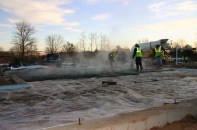 A Purinton Builders crew places a residential foundation slab at dawn on a winter morning. With the appropriate mix design and good control of the concrete temperature in the ready-mix truck, says Purinton, his crews can safely place slabs in freezing weather, without a heated enclosure or sometimes, even blankets.
