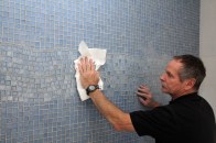 Author Tom Meehan wipes the grout haze from a decorative glass-tiled wall.
