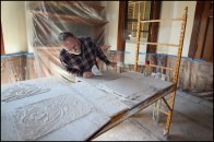 Master plasterer Ron Bisson inspects replacement plaster flatwork, which will be used to restore the main entry hall ceiling of the Fairbanks Mansion in St. Johnsbury, Vermont. An existing sponge finish (as well as years of built-up paint) made blending the new repair work to the existing rustic ornamental ceiling a challenge.