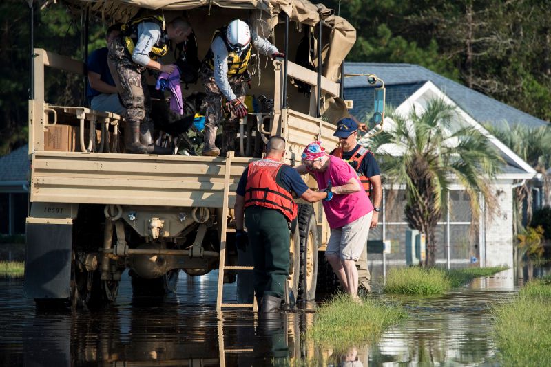 Coast Guard members assigned to the Atlantic and Pacific Strike Team assist an elderly woman into an Army National Gaurd high-water transport vehicle Sept. 20, 2108, in a flooded neighborhood in Longs, South Carolina. (U.S. Coast Guard photo by Petty Officer 3rd Class Ryan Dickinson)