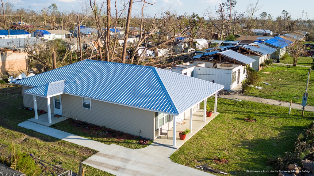 This affordable house, built under the "Habitat Strong" program, is one of six that survived Hurricane Michael unscathed. Surrounding older homes show severe roof damage.