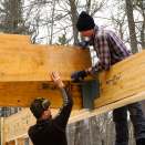 Carpenters Alex Strugatskiy and Ryan Bielenda assemble an LVL carrying beam in place, supported by a steel connector bolted into the center of an Anthony Power Beam glue-lam over a long window opening.