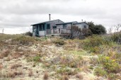 A view of the dune shack showing the main volume of the house stepping down to the bedroom and toilet room. Exterior deck is accessed from the screen porch.