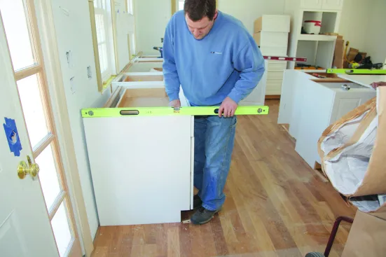 Before scribing cabinets to the wall, the tops should be level and in plane with the tops of the other base cabinets. The face needs to be parallel with the other cabinet faces so that when the scribe is cut, the faces will be in plane as well.