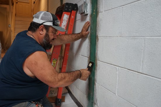 Toby Bonilla of Great Lakes Builders smooths out the two-part epoxy over a carbon-fiber strap used to reinforce a block foundation wall.