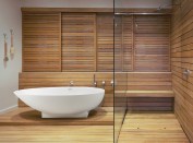Soaking tub and shower surrounded by wood walls in modern, luxury home showcase interior bathroom