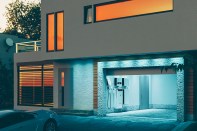 concept of a home battery energy storage system located in the garage of a modern family house in a futuristic blue light illuminating the evening atmosphere of a quiet street. 3d rendering.