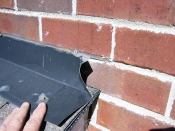 Counterflashings installed in saw-cut kerfs--such as this one above a shed roof--do nothing to divert water from the cavity behind the brick. These installations have a high rate of failure; copious amounts of caulk and the presence of nails or screws are dead give-aways that the flashing is useless.