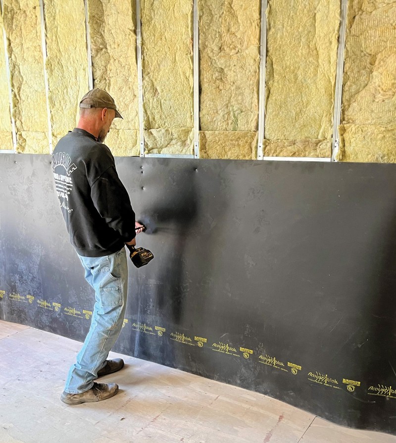 Mass-loaded vinyl is installed over a row-house party wall.
