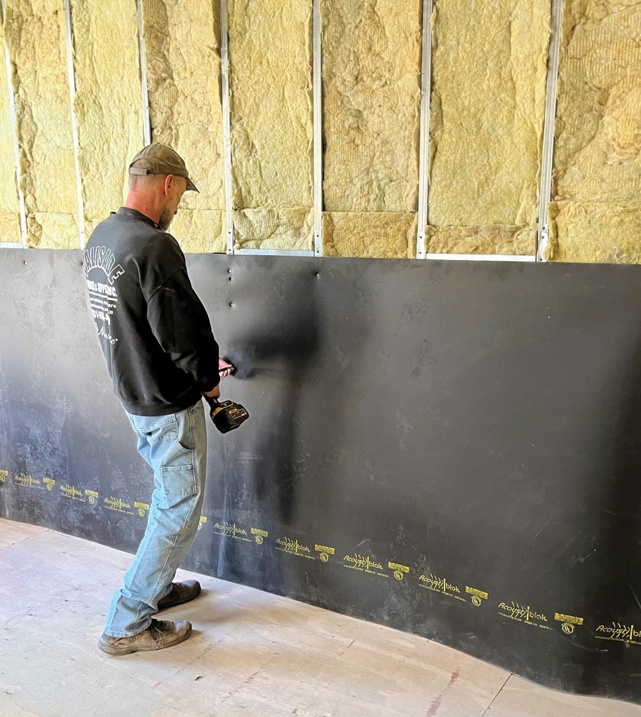 Mass-loaded vinyl is installed over a row-house party wall.