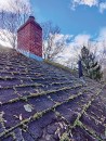 This north-facing roof is clad with architectural laminated shingles, which are made up of multiple layers of asphalt-coated fiberglass that can trap organic debris and provide food for moss growth.