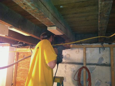 After redirecting the gas line, sewer pipe, and electrical wiring, we began work on the floor system. Lead carpenter Danny DuCouto hammer-drilled out four new beam pockets for the steel in the existing brick party walls.