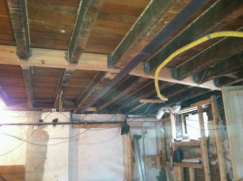 With steel and Microlams roughly in place, we shimmed the steel level and applied non-shrink grout at the beam pockets. We connected the existing joists to the Microlams with joist hangers and clip angles, then removed the shoring.