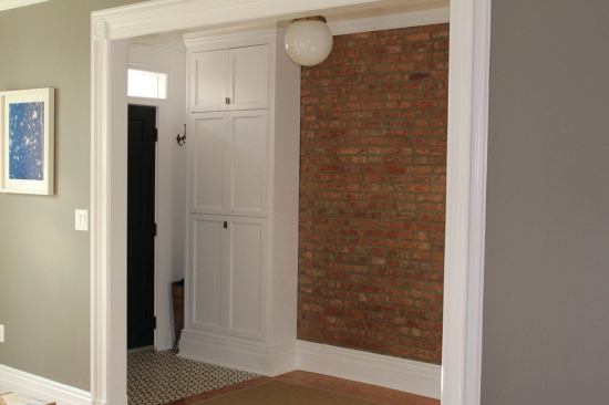 The dedicated entry on the first floor featured a powder room, closet, and new 6-foot opening to the living room. We cleaned and sealed the existing brick party wall and installed a built-in closet to hide the electrical panel by the new front door.