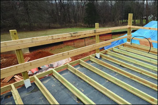 Though not usual, sleepers may be fastened to 2-bys laid on the flat, which helps distribute loads over a wider area, particularly when a protection board is not installed between the roof membrane and insulation or when a roof insulation with a lower compressive strength is used. Here, the guardrail posts are secured to the framing below and flashed with TPO post sleeve flashing, and the EPDM protection layer is fit around the posts.