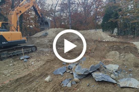 The boulder seen in the last slide cannot be moved or dug out. Blasting and drilling cannot be used in the densely developed neighborhood, so the excavation contractor breaks up the rock by continuously dropping a one-ton steel weight nicknamed "The Headache Ball" from the bucket of his excavator. 
Click here to watch an action video.