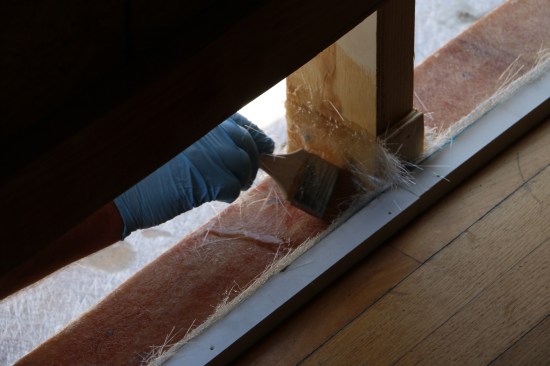 Installer uses a disposable paintbrush to soak the fiberglass mat in problem areas such as these threshold intersections.