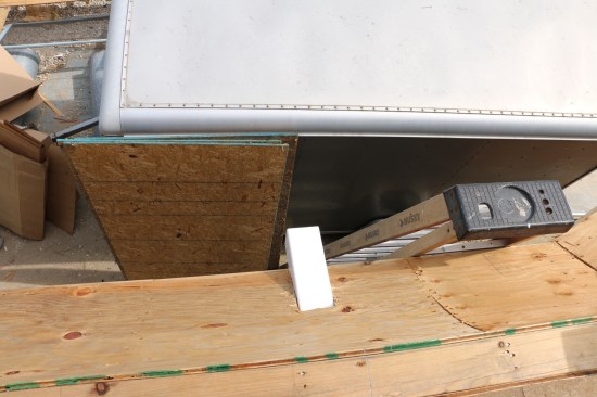 The square tube that forms the scupper extends out beyond the eave.