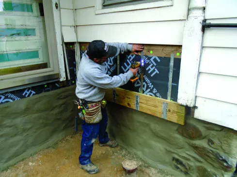 A screw in each strap holds the side-wall ledger in place. It will act as a guide for setting the rest of the deck perimeter.