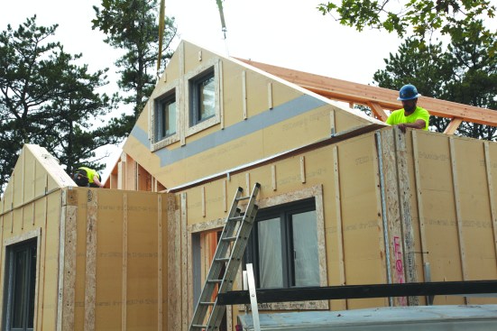 After attaching gasket material to the top plates of the walls, the crew sets the gables.