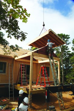 After installing the porch ridge beam, the crew installs the porch roof panels.