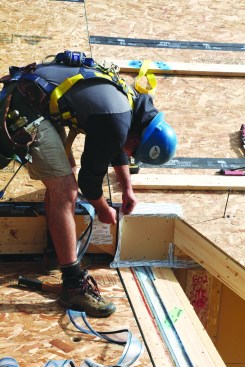 A crew member layers the various tapes and gaskets for a crucial wall–roof–deck intersection.