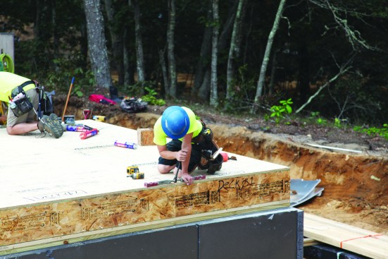 As each floor panel is set in place, the crew draws the panels together with specialized ratchets. The panels are then fastened to the sills from below.