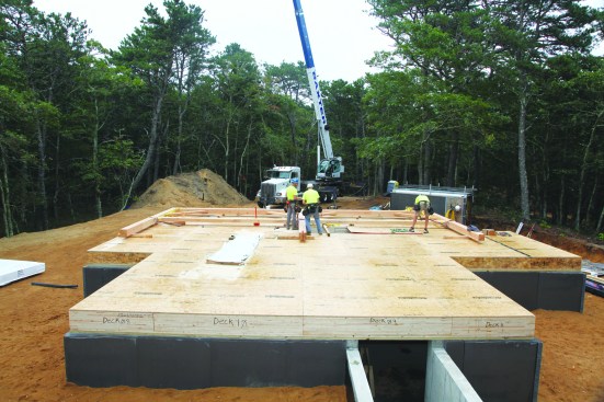 Unity Homes often have a timber-frame component, and this house was no exception. After setting the floor deck panels, the crew assembles a timber-frame bent made from glulam lumber that was cut in the factory.