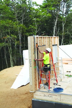 As each panel is set and braced, the crew attaches the gasket material to the corner of the panel where it meets the adjoining wall panel.