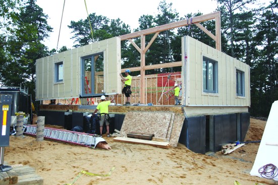 After raising the timber-frame bent, the crew continues to stand the walls around the house.