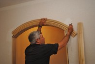 To lay out the miter joint where an eyebrow arch joins the side jambs, first extend the side jamb lines up the wall. Then trace the arch profile extending the lines until they intersect with the side jamb lines.