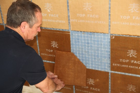 Start at one corner and slowly pull off the paper diagonally, keeping your hands close to the wall.