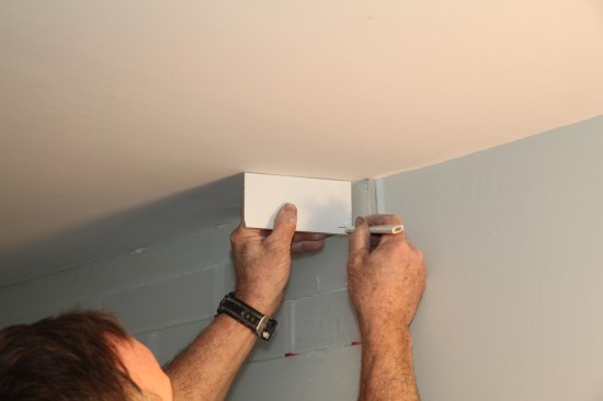 Place the tile against the ceiling in the area where it’s to be installed, and mark the amount that needs to be removed.