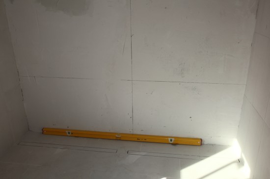 To complete the initial layout, set a level on the shower floor and measure up the distance of two full sheets of mosaics from the top of the level.
