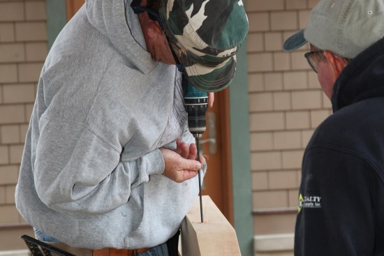 A crew member carefully drills slightly over-size holes for the screws. A Forstner bit creates pockets for the screw head on the top side of the beam.