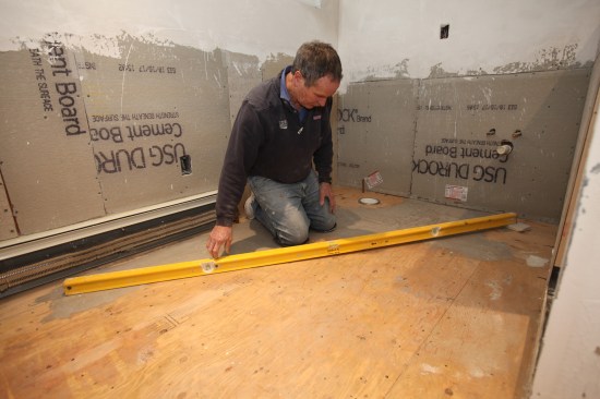 In this L-shaped bathroom, one corner was very high, dropping a full inch toward the built-in shower.