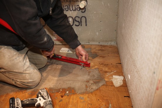 The author uses the screw to set the height of the gauge rake for spreading the liquid leveler.