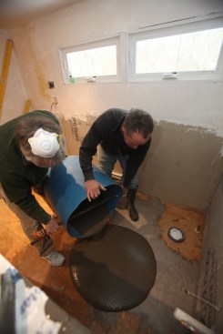 Two crew members dump the initial bucket of mix in the corner where the compound will be the deepest. 