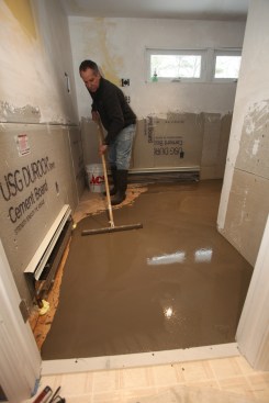 The author uses a squeegee to smooth out the leveler in front of the door and to feather the liquid up to the high corner.