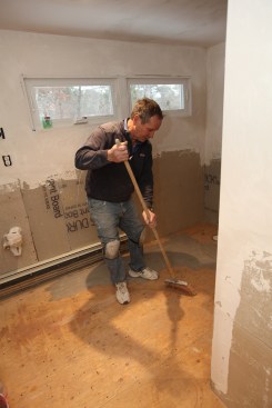 Before the primer can go down, the author sweeps the floor clean of dirt and debris.