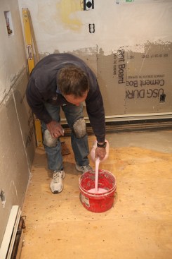 Author pours pre-mixed primer into a bucket.The primer helps with adhesion and helps to seal the underlayment so that it doesn't absorb water out of the leveler.