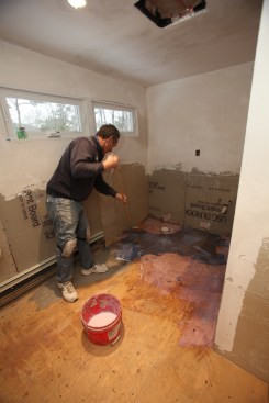 A coarse floor broom is perfect for applying a generous coat of primer on the underlayment.