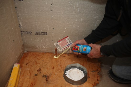 Expanding foam seals the gap around the plumbing supply pipe for the toilet.